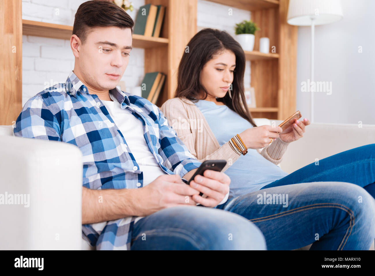 Junge schöne Paar an Smartphones starrte Stockfoto