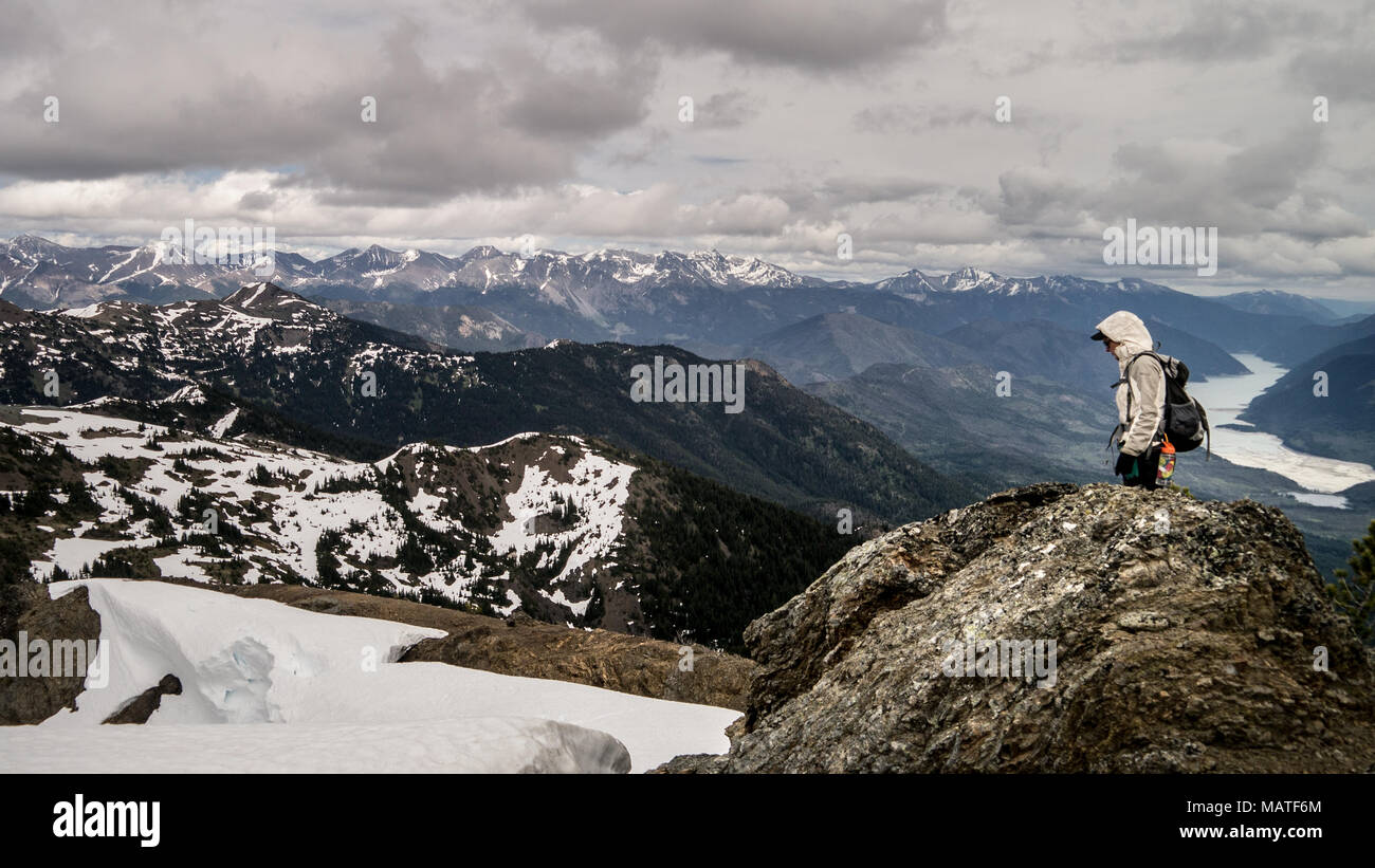Weibliche Wanderer Wandern auf einem Bergrücken mit Schnee Banken im frühen Frühling. Dramatische und schöne Landschaft im Hintergrund (Gold Bridge, BC, Kanada Stockfoto