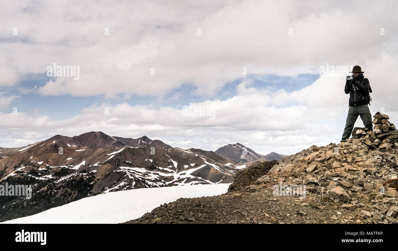 Männliche Wanderer auf einem Bergrücken fotografieren das atemberaubende Landschaft. In der Nähe von Gold Bridge, BC, Kanada Stockfoto