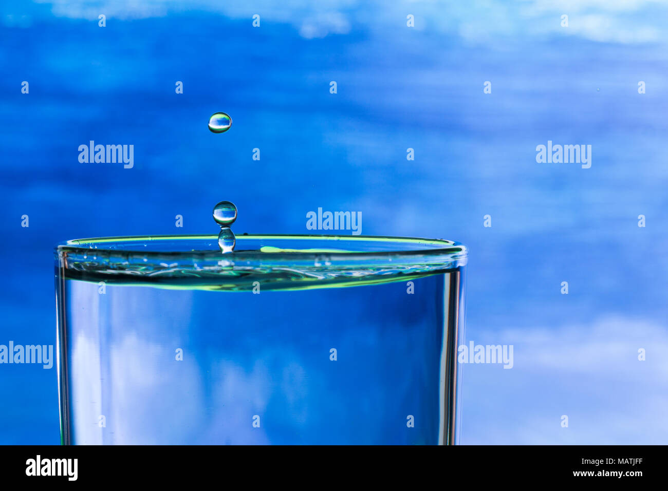 Wassertropfen spritzen in einem Glas Trinkwasser Stockfoto