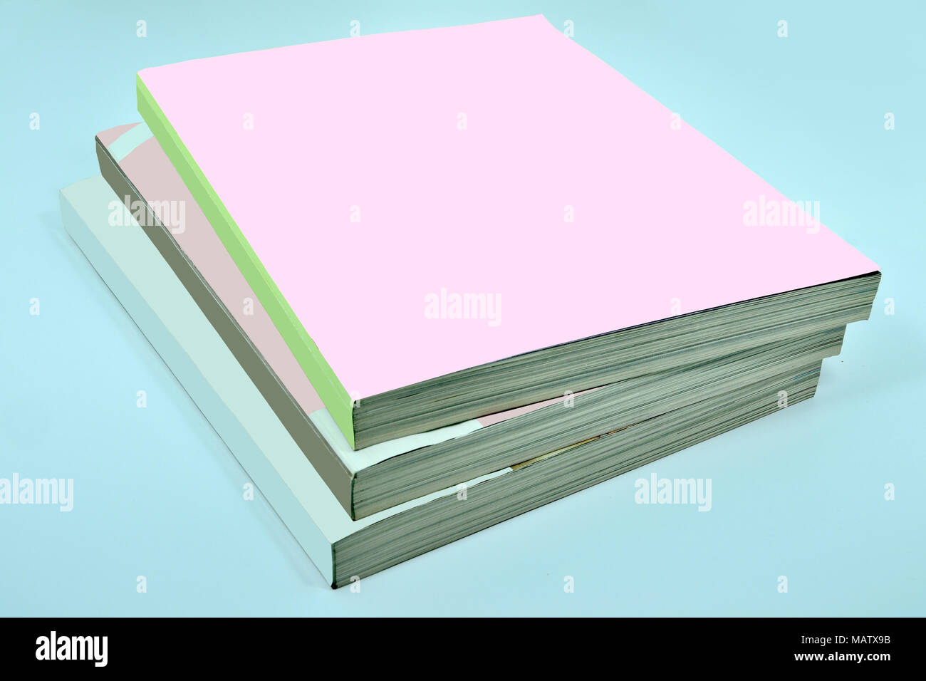 Stapel von drei dicke Zeitschriften oder Bücher, Kataloge mit einem leeren Pink soft cover auf einem blauen Hintergrund - ein mock up für das Demonstrieren Sie Ihr Design Stockfoto