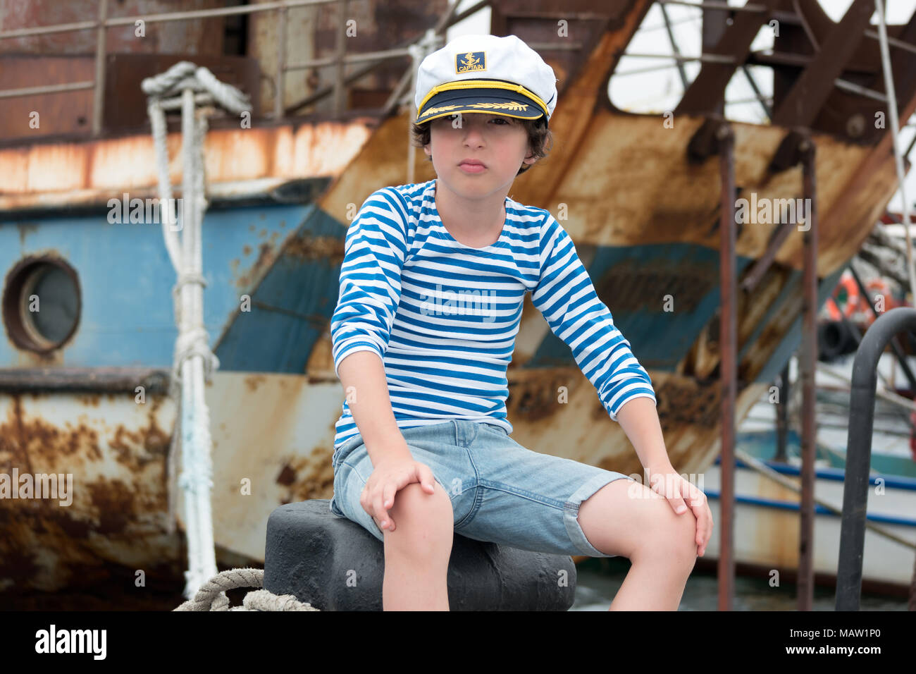 Porträt eines Jungen in einer Weste (Telnyashka) und Kapitän Kappe vor dem Hintergrund einer rostig und alt. Stockfoto