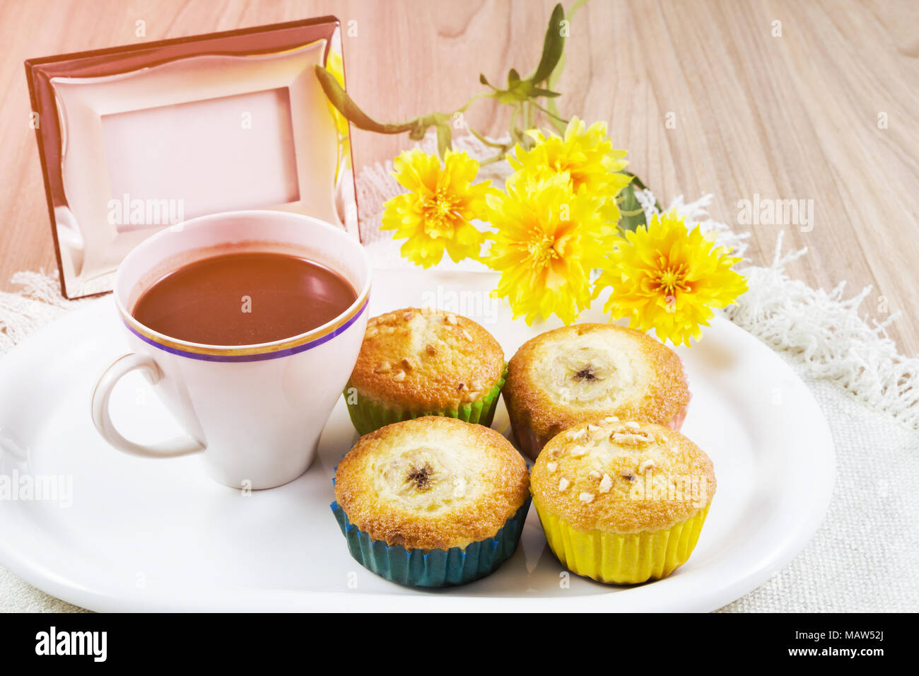 Tasse Heissen Kakao Oder Eine Heisse Schokolade Und Banane Cupcake In Weisser Teller Am Tisch Mit Gelben Fake Blumen Mit Sonnenschein Am Morgen Hintergrund Konzept Ti Stockfotografie Alamy