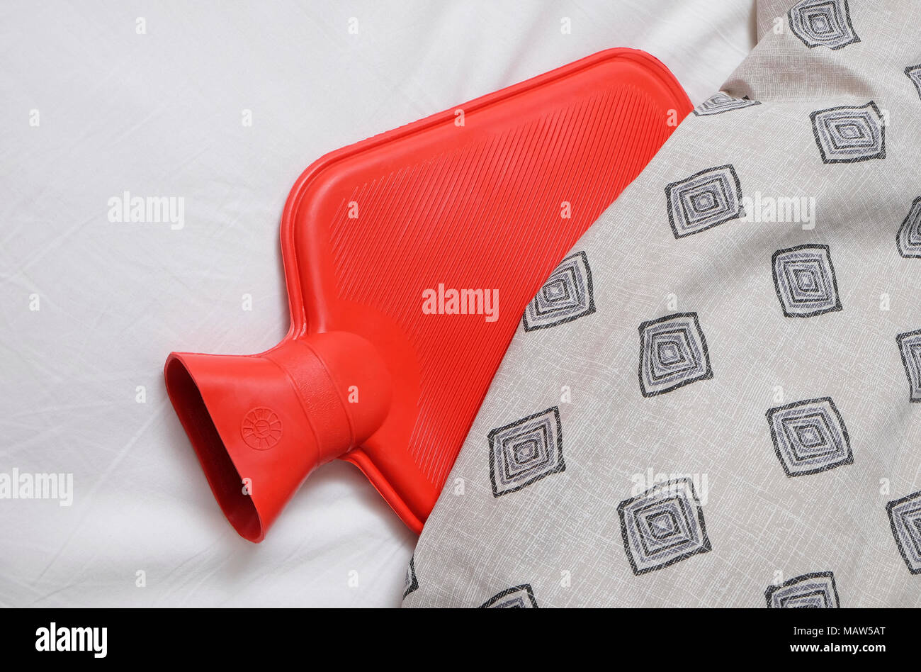 Rote Wärmflasche im Bett Stockfoto