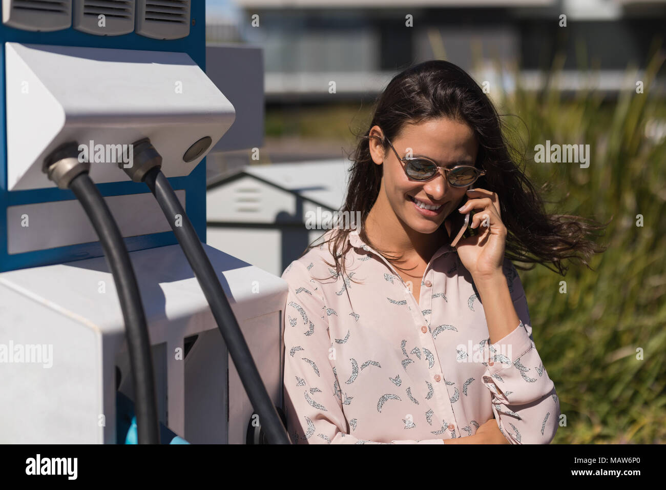 Frau Gespräch am Handy an der Ladestation Stockfoto