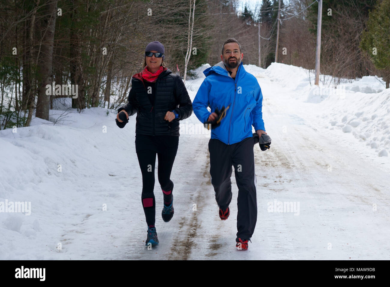 Paar, Jogger, Mann und Frau sind Joggen in einem Wald Straße im Winter. Stockfoto