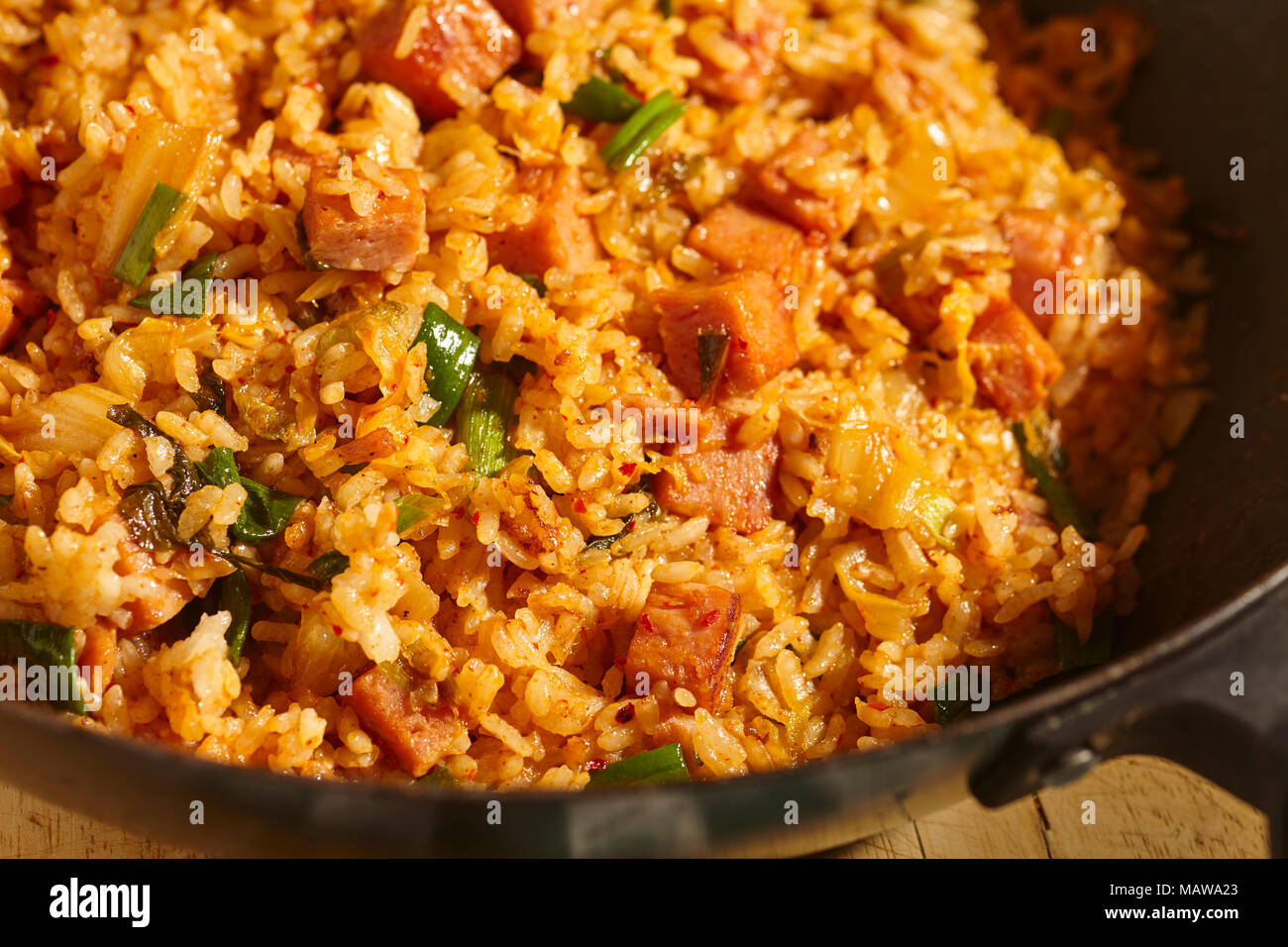 Spam und Kimchi gebratener Reis in einem schwarzen Stahl Wok, ein klassisches Gericht in Korean Home Kochen Stockfoto