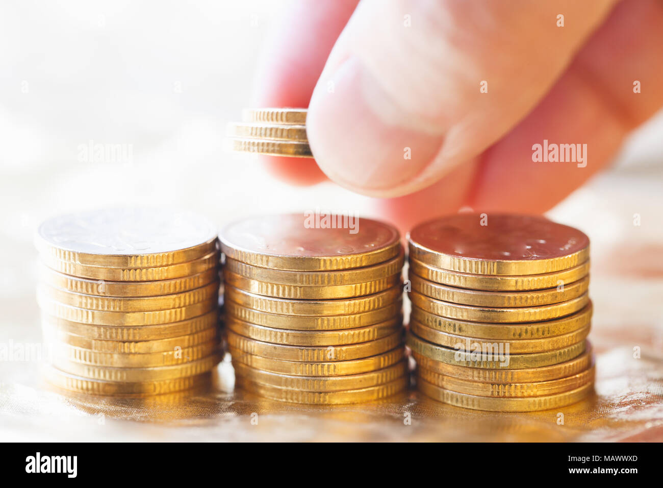 3 Stapel von Goldmünzen senden Sie das goldene Licht Stockfoto