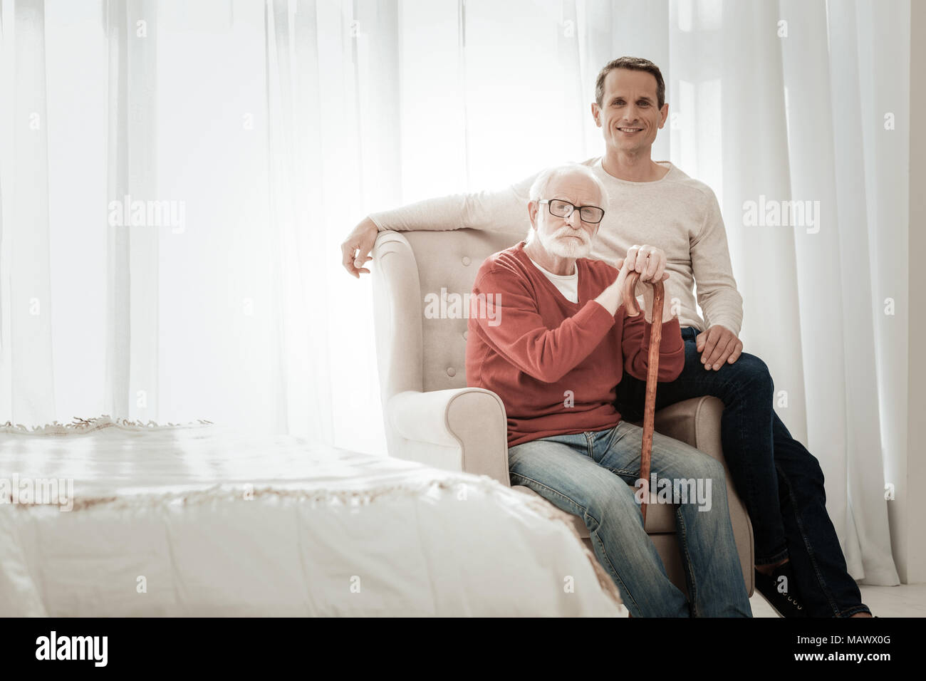 Senior unshaken Mann sitzt auf dem Stuhl und gerade auf der Suche. Stockfoto
