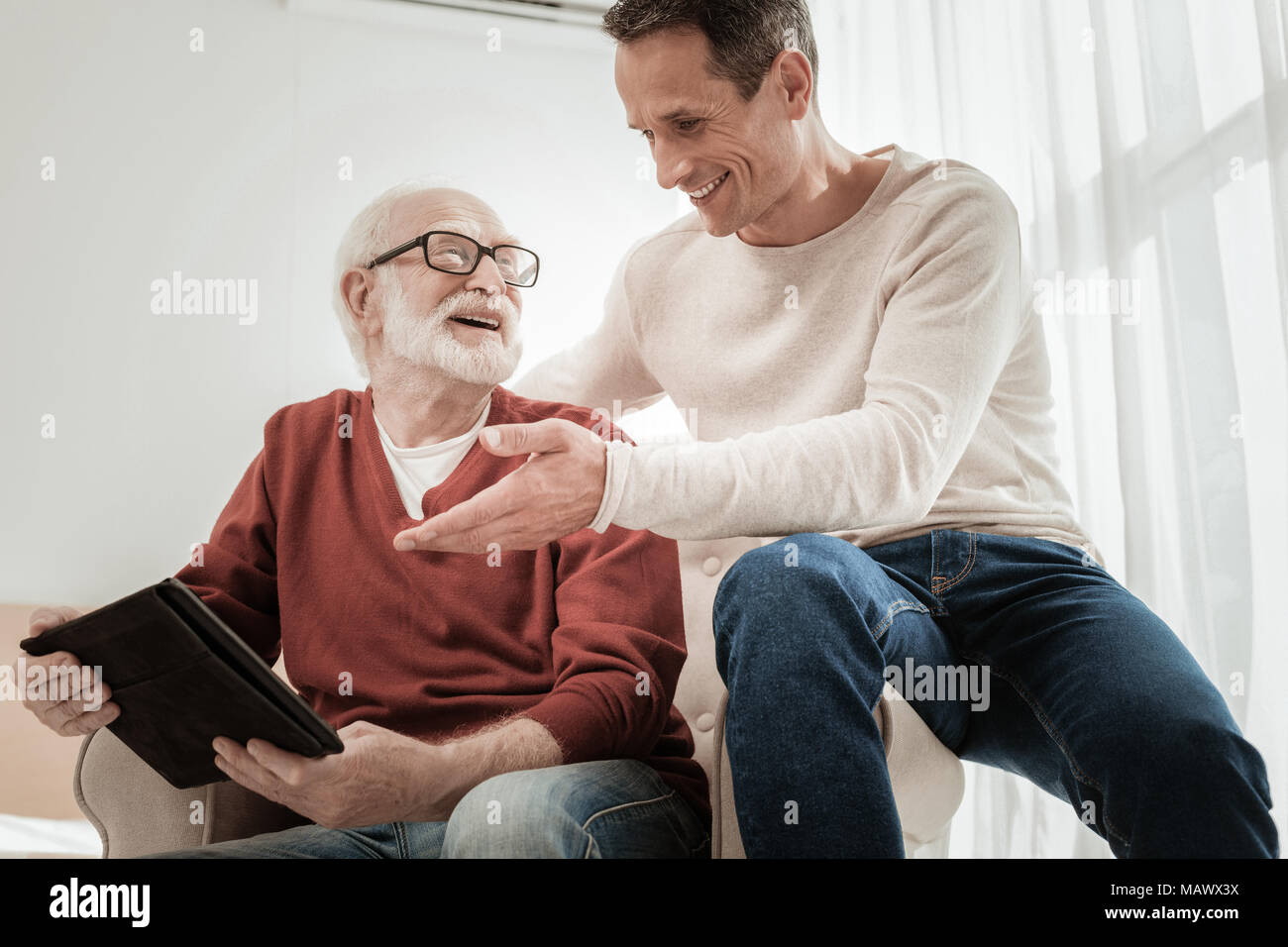 Senior unshaken Mann und lächelnd der Tablette. Stockfoto