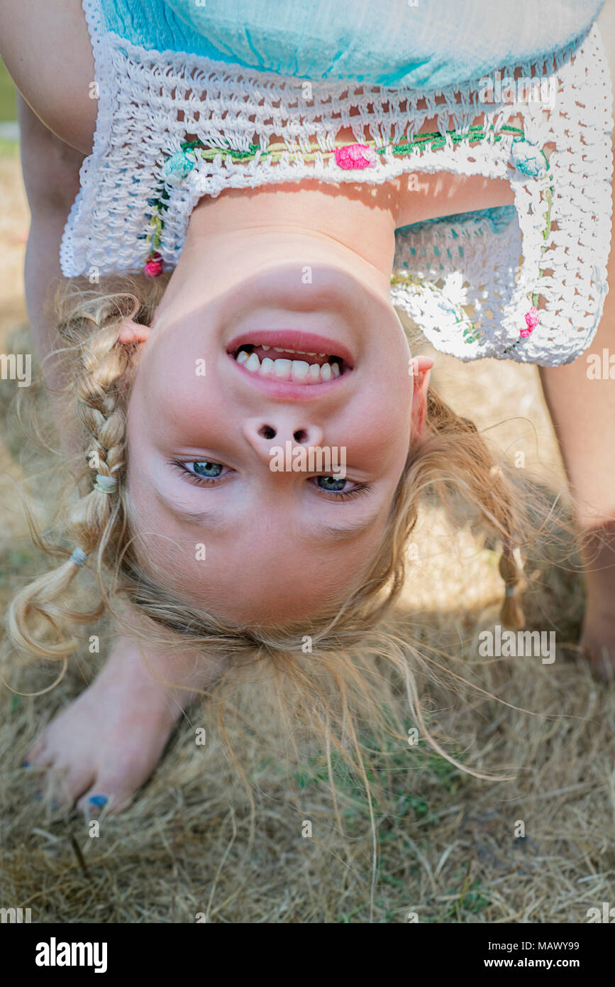 Ein junges Mädchen, 4-6 Jahre alt, auf den Kopf gehalten wird. Stockfoto