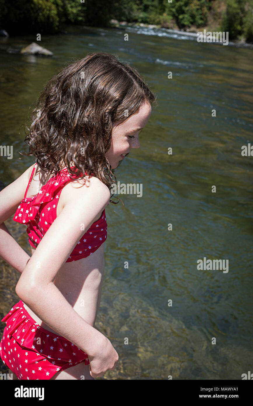 Ein junges Mädchen im Badeanzug neben der North Santiam River. (7-9 Jahre alt) Stockfoto
