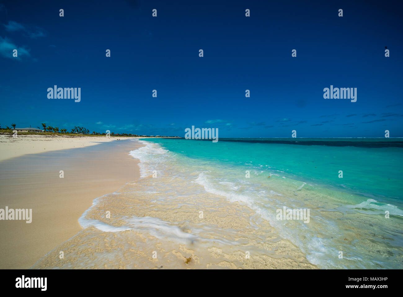 Schönen ruhigen einsamen tropischen Strand mit goldenem Sand und sanften blauen Ozean plätschern am Ufer auf einer idyllischen Insel Wochenende für einen Sommer vacat Stockfoto