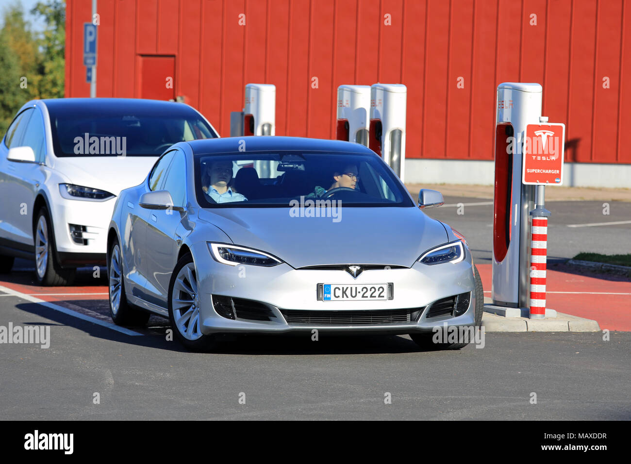 TOIJALA, Finnland - 24 September 2017: Zwei junge Männer in Silber Tesla Facelift Modell S elektrische Auto Kompressor Station, mit weißen Tesla Modell Stockfoto