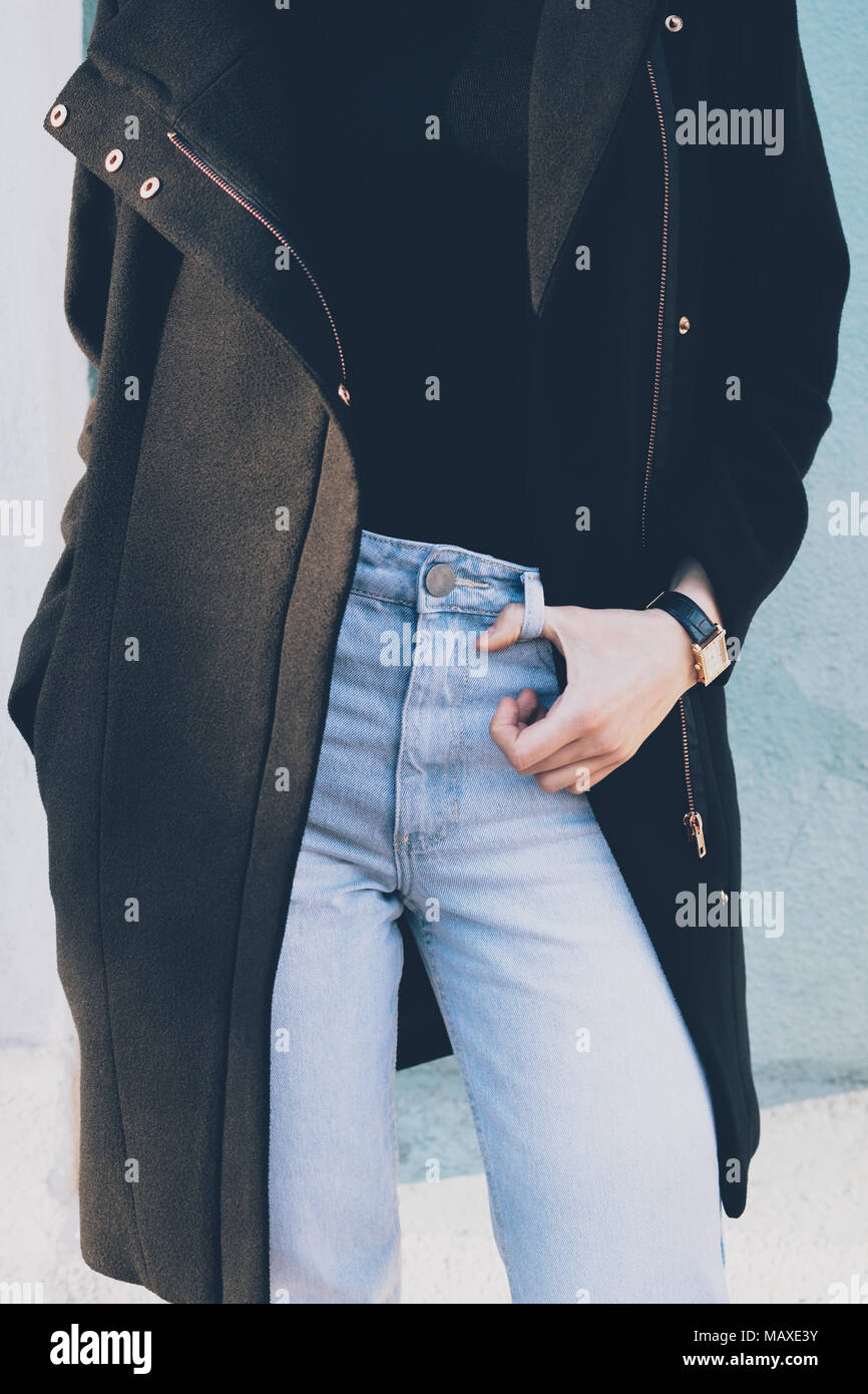 Details stilvolle Winter, Frühling oder Herbst Outfit. 7/8-Foto von schlanken jungen Frau mit schwarzen Mantel, blau mit hoher taille Jeans und gold Wrist watc Stockfoto