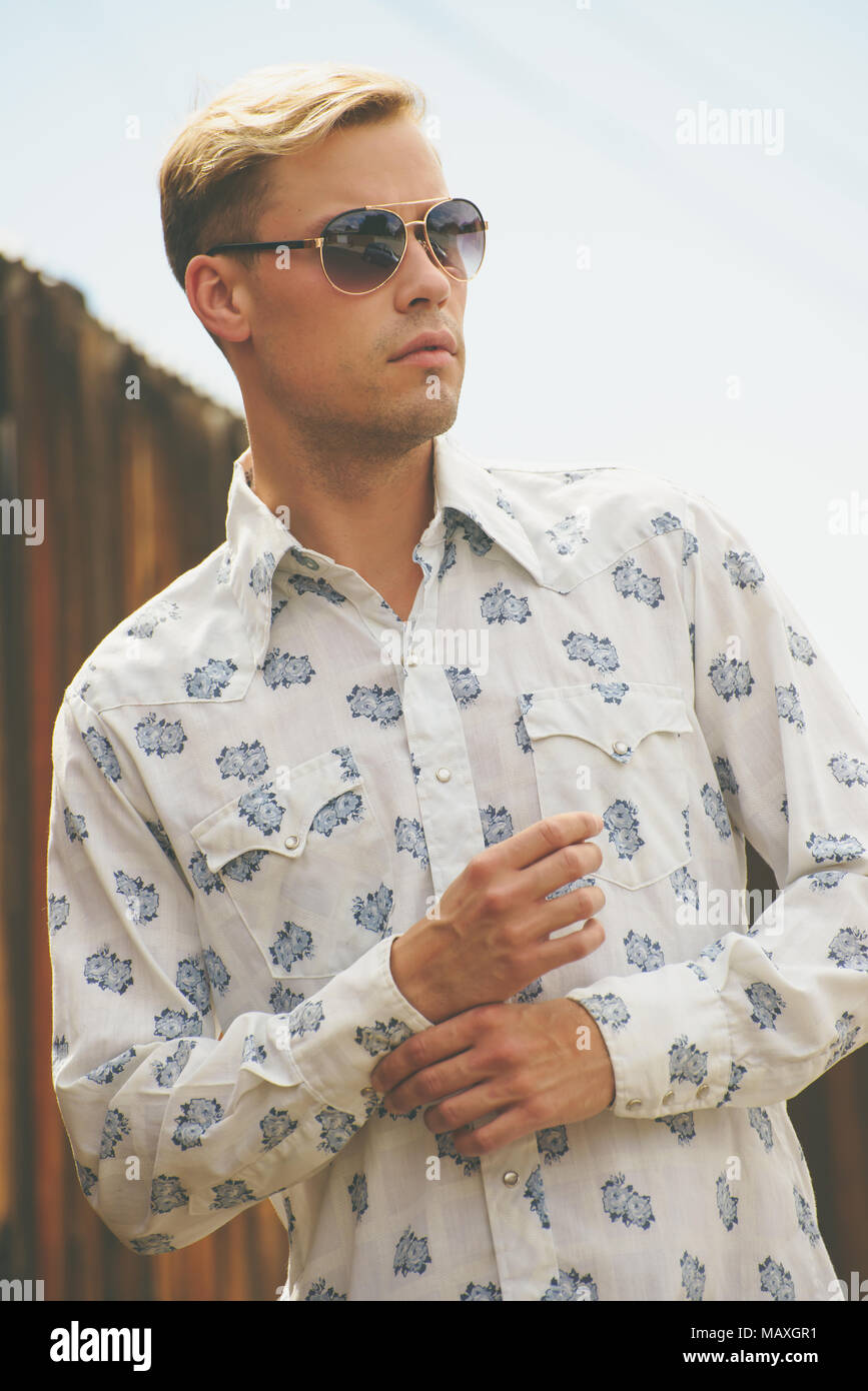 Ein kaukasischer Mann, männliches Modell posiert in Sonnenbrille, tragen Männer 70s Vintage Shirt, einen Men's Vintage Mode redaktionelle Konzept. Stockfoto