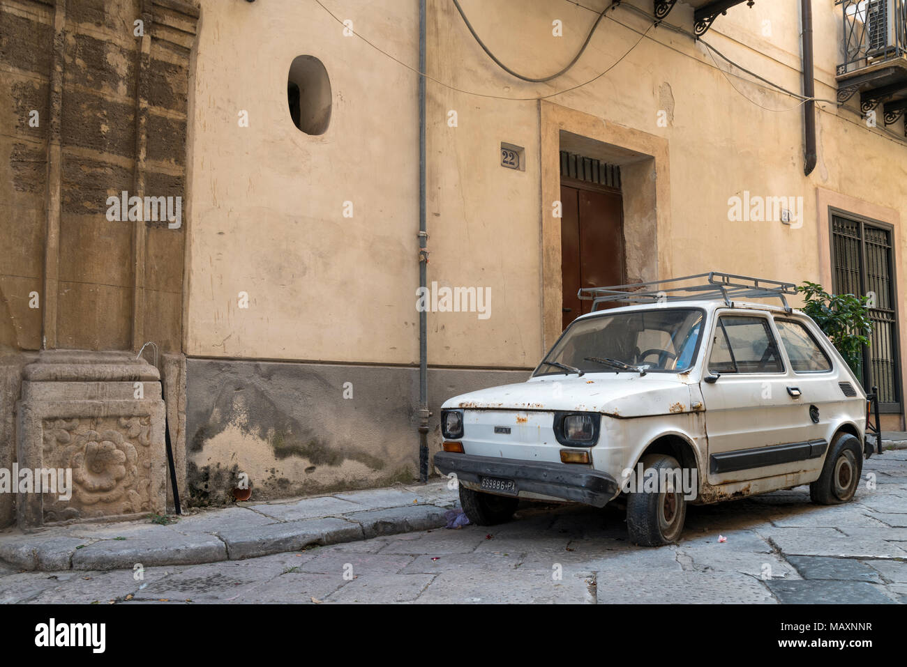 Einen alten weißen Fiat 126 mit plattem Reifen, auf einer Straße in Palermo, Sizilien, Italien aufgegeben. Stockfoto