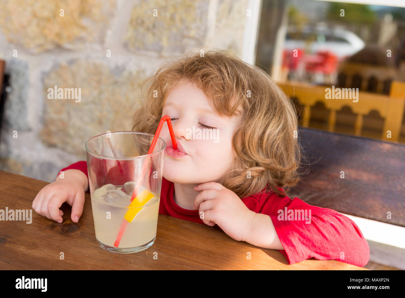 Kleines Kind, das ein alkoholfreies Getränk durch einen Plastikstroh trinkt, Spanien Stockfoto