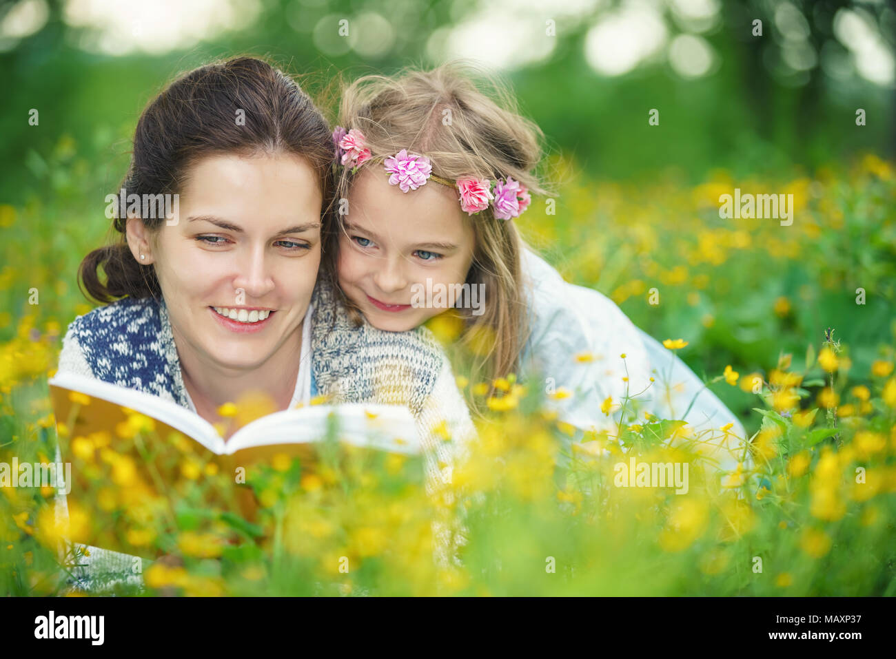 Mutter und Tochter liegen auf frühlingswiese genießen Sie Buch Stockfoto