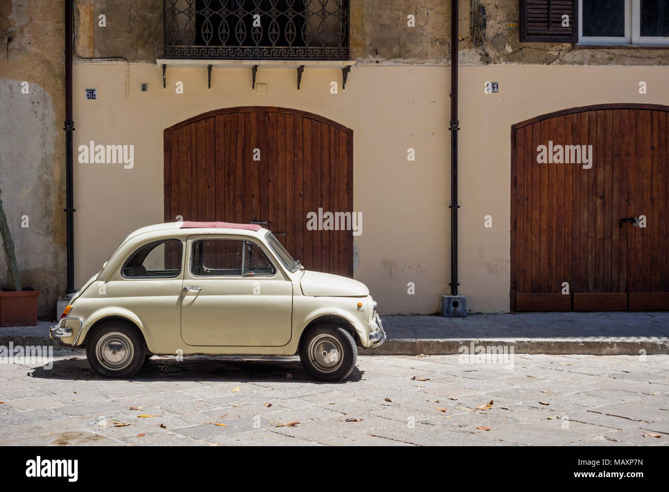 Einer alten cremefarbenen Fiat 500 mit roten Schiebedach, außerhalb eines Gebäudes in Palermo, Sizilien geparkt. Stockfoto