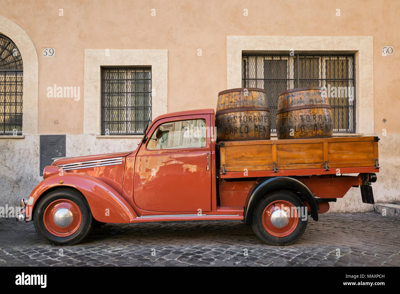 Eine alte rote Fiat 1100 flachen Bett van mit hölzernen Weinfässer im Rücken, außerhalb Ristorante Carlo Menta in Rom, Italien, geparkt. Stockfoto