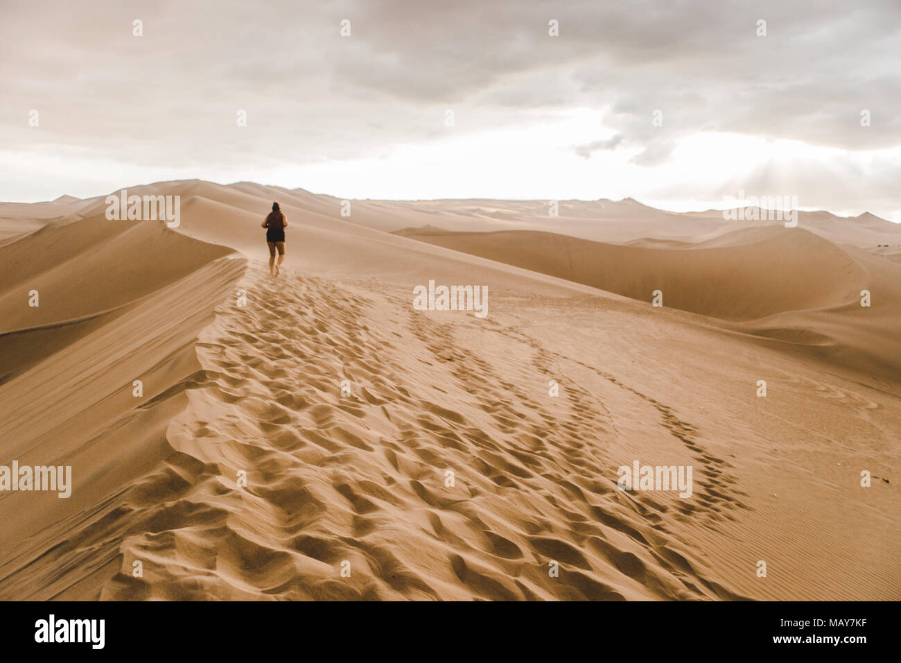 Junge tausendjährigen Frau tourist/Reisenden geht über eine Sanddüne in der Wüste mit einem roten Rucksack in Huacachina, Peru Stockfoto