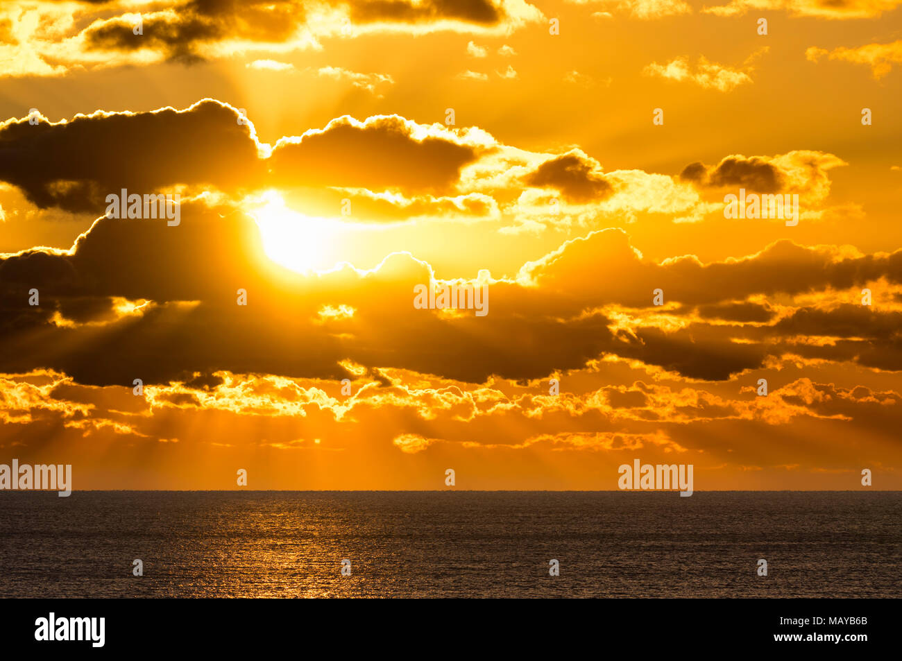 Dramatischer Sonnenuntergang über Wasser mit Strahlen der Sonne hindurch und Beleuchtung bis zum Meer. Stockfoto
