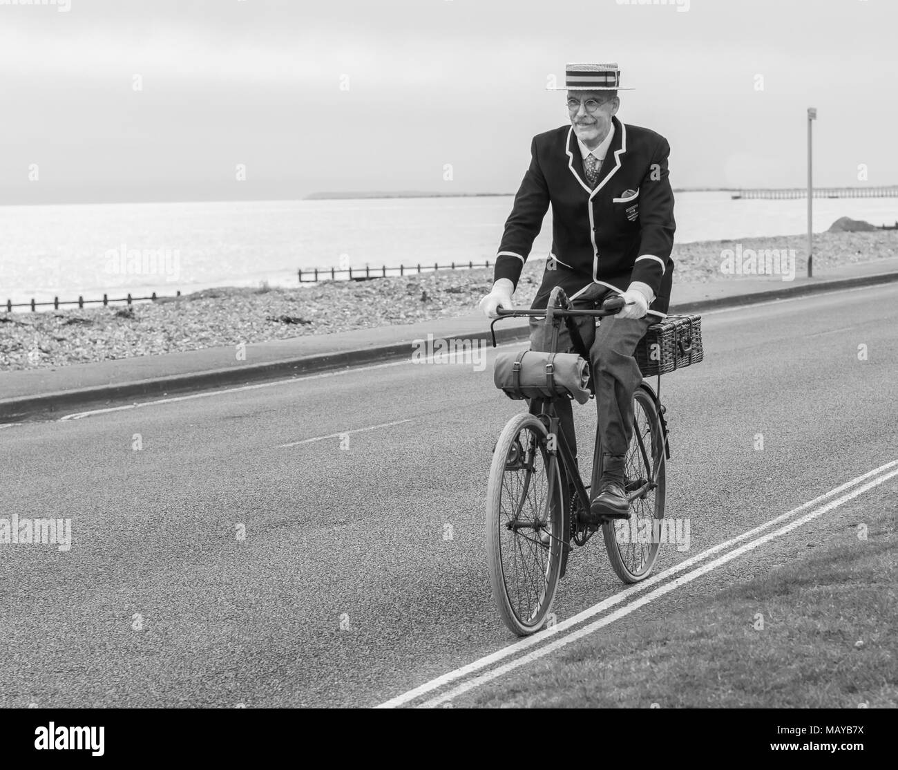 Älterer Mann, einem viktorianischen Fahrrad in Periode Kleidung und Stroh Kreissäge Hut gekleidet, in Großbritannien, in Schwarz und Weiß. Alte Radfahrer reiten vintage Bike. Stockfoto
