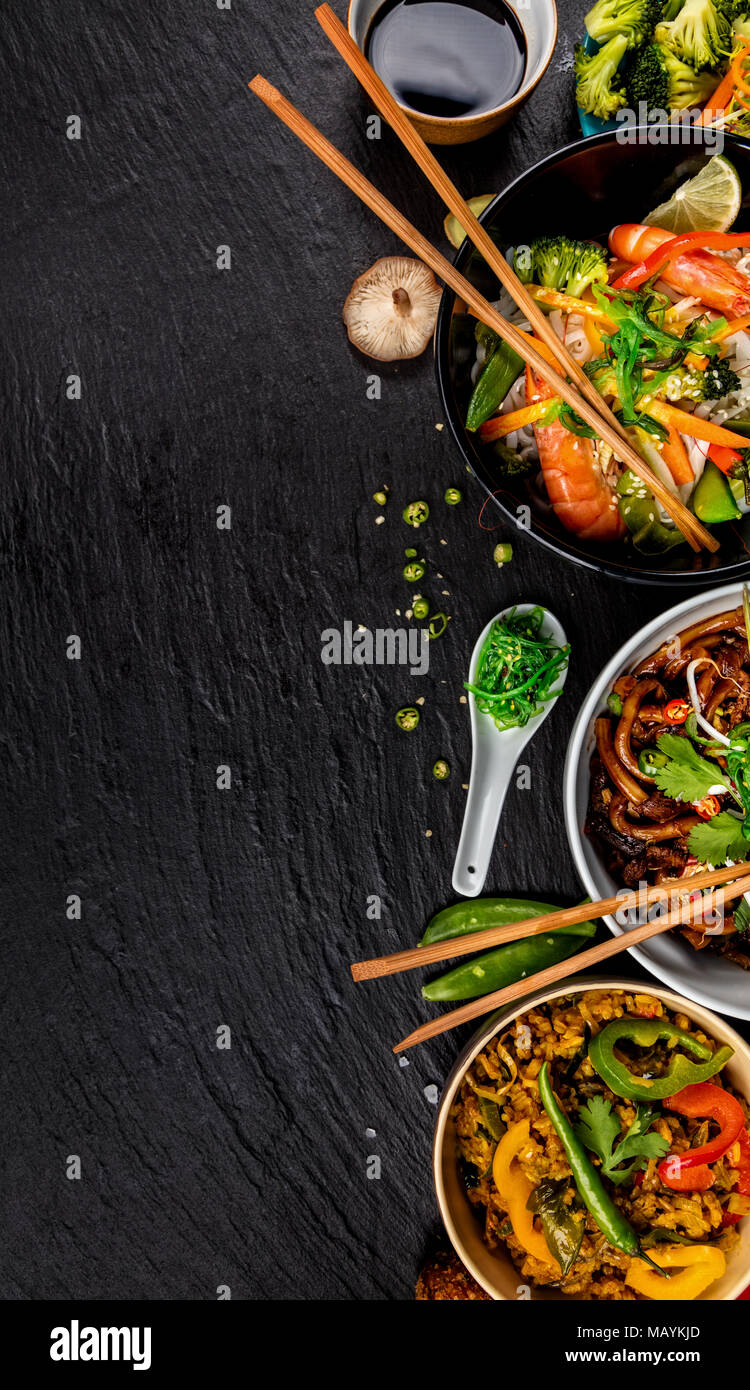 Asiatische Lebensmittel Variation mit vielen Arten von Mahlzeiten. Kari Reis, Nudeln und Gemüse. Ansicht von oben, auf schwarzen Stein serviert. Stockfoto