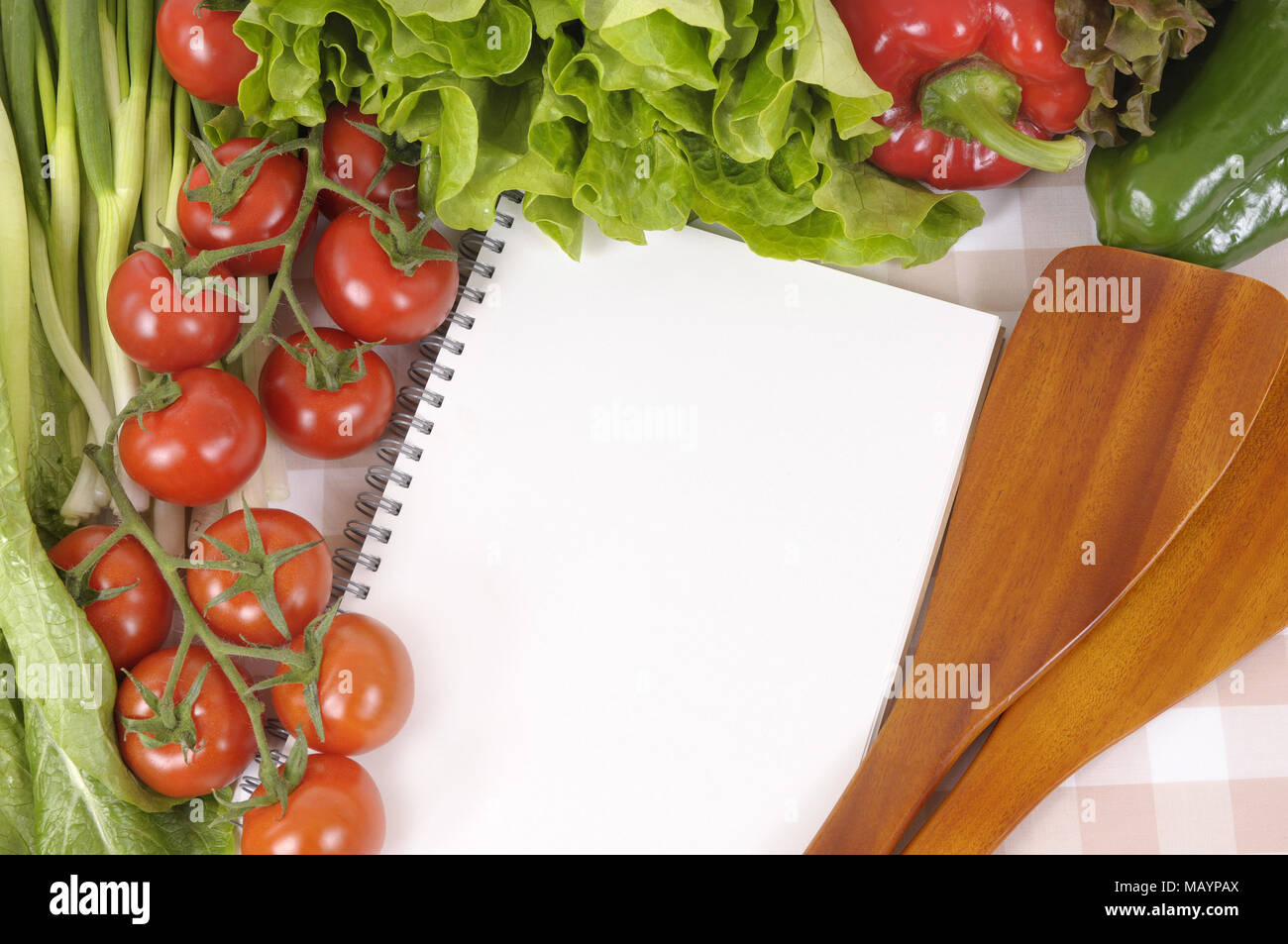 Auswahl an Salat Gemüse mit leeren Rezeptbuch oder Shopping Liste auf eine Tischdecke. Stockfoto
