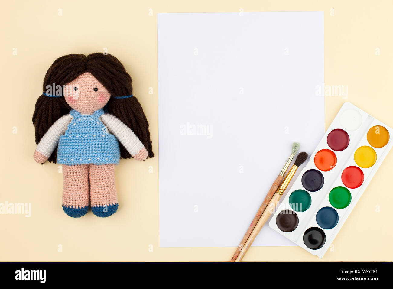 Oder Puppe mit braunen Haaren, Pinsel und Wasserfarbe und leer für Text auf weichem gelben Hintergrund Stockfoto