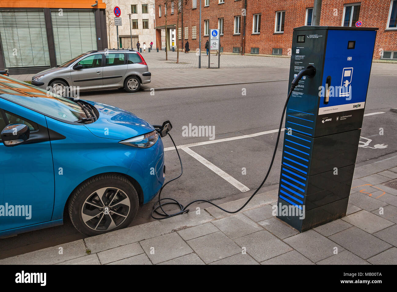 Elektrische Auto ist an der grünen Elektrizität Ladestation mit Ladekabel, München, Bayern, Deutschland Stockfoto