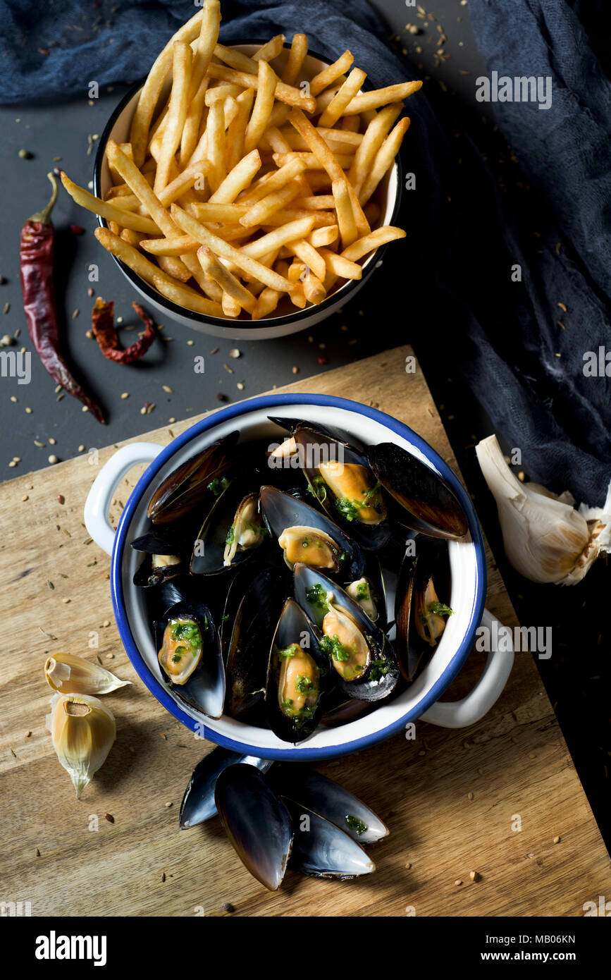 Moules - Pommes frites, Muscheln und Pommes frites, die typisch für Belgien, auf einem rustikalen Holztisch Stockfoto