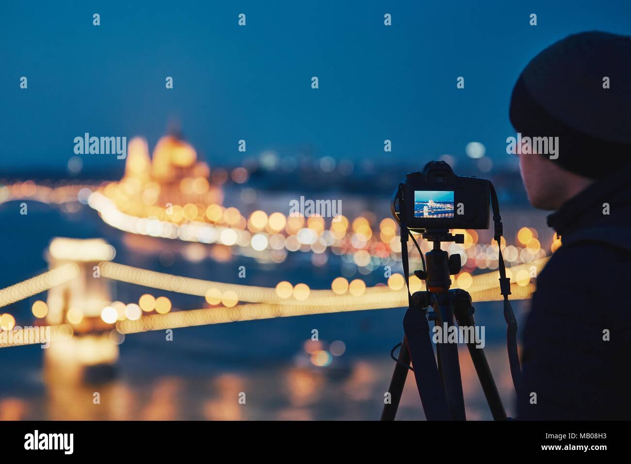 Fotograf mit Stativ. Junger Mann, Foto mit seiner Kamera in der Nacht Stadt. Budapest, Ungarn. Stockfoto