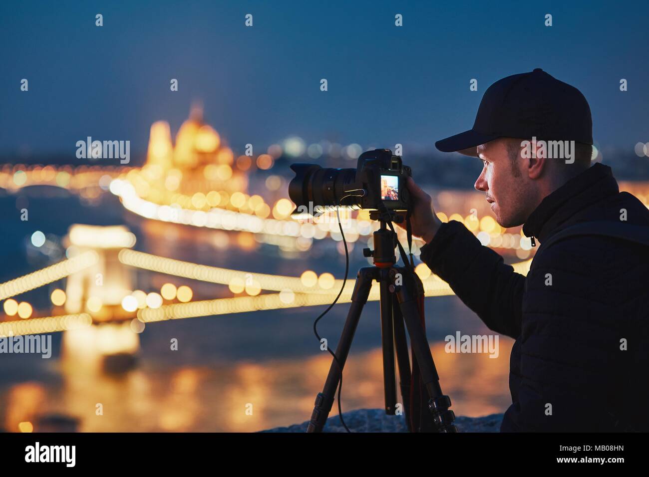 Fotograf mit Stativ. Junger Mann, Foto mit seiner Kamera in der Nacht Stadt. Budapest, Ungarn. Stockfoto