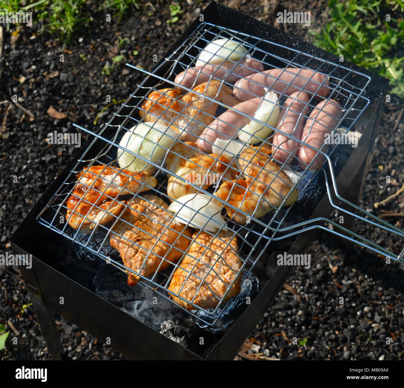 Blick von oben auf eine Vielzahl von gebratenem Fleisch, Huhn, Zwiebeln, Kartoffeln und Würstchen auf einem Grill Rack Stockfoto