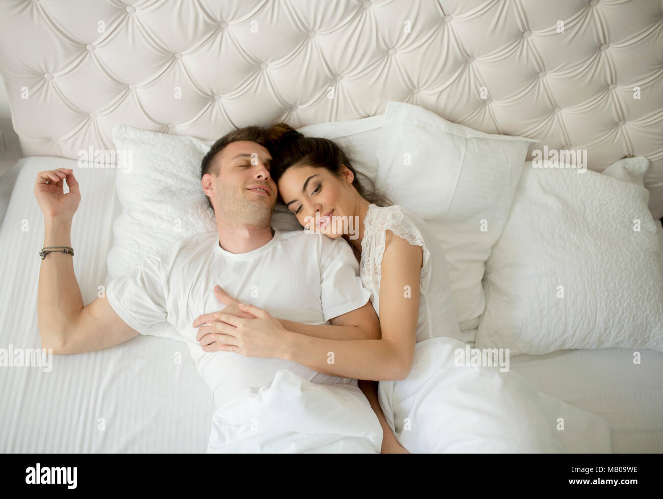 Liebevolle junge Paare, die in den weißen Bett Stockfoto