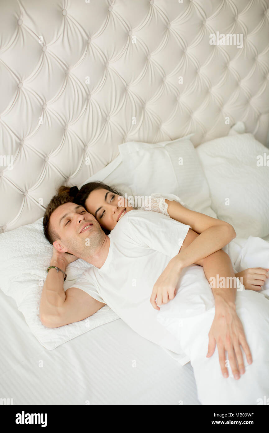 Liebevolle junge Paare, die in den weißen Bett Stockfoto