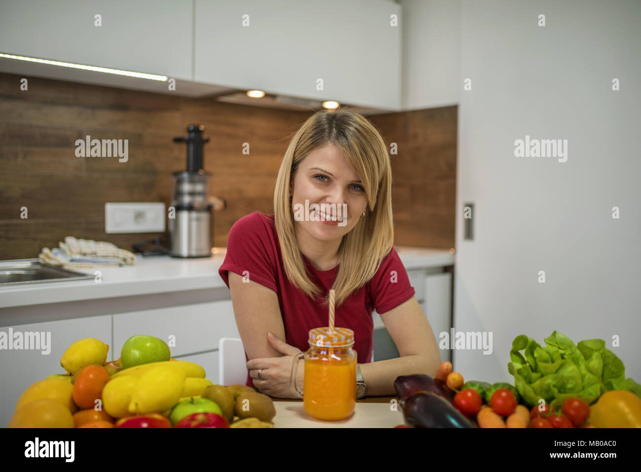 Junge Frau trinkt Smoothie in der Küche. Nahaufnahme, Porträt der jungen Frau in der Küche. Gesunde Ernährung - Gemüse Salat. Diät. Diät Konzept. Stockfoto