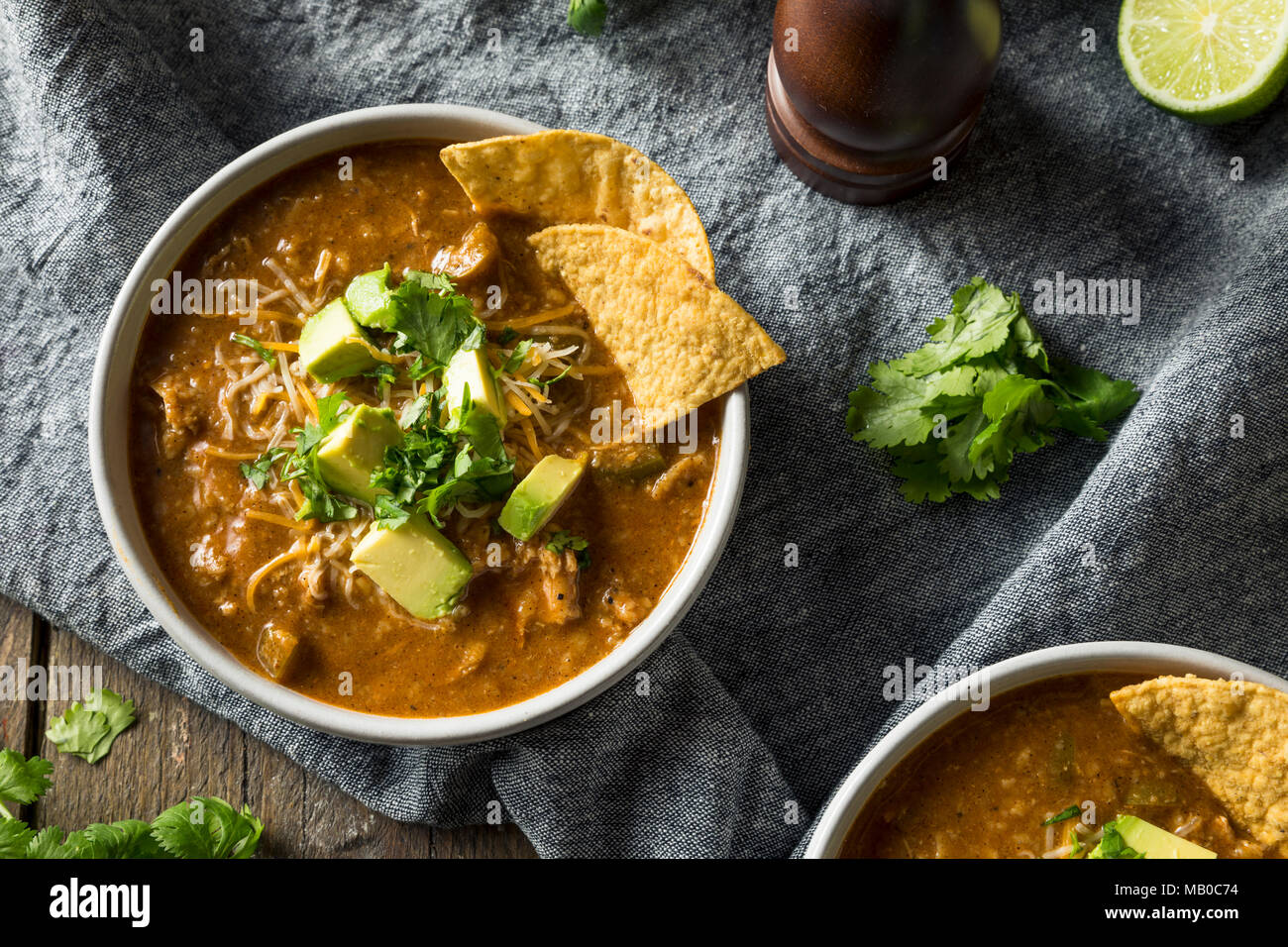 Würzige selbstgemachte Tortilla Soup mit Käse, Koriander und Limette Stockfoto