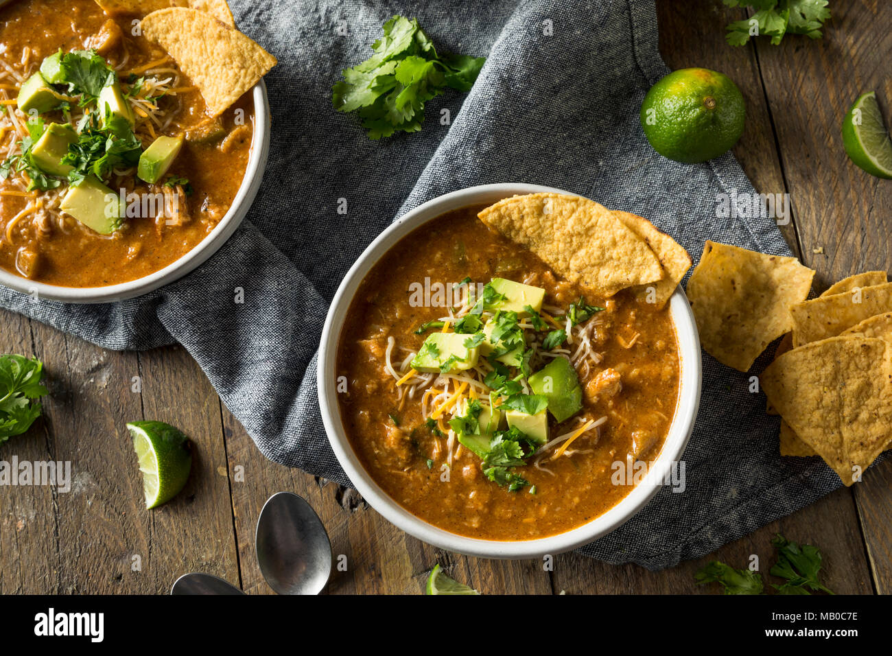 Würzige selbstgemachte Tortilla Soup mit Käse, Koriander und Limette Stockfoto