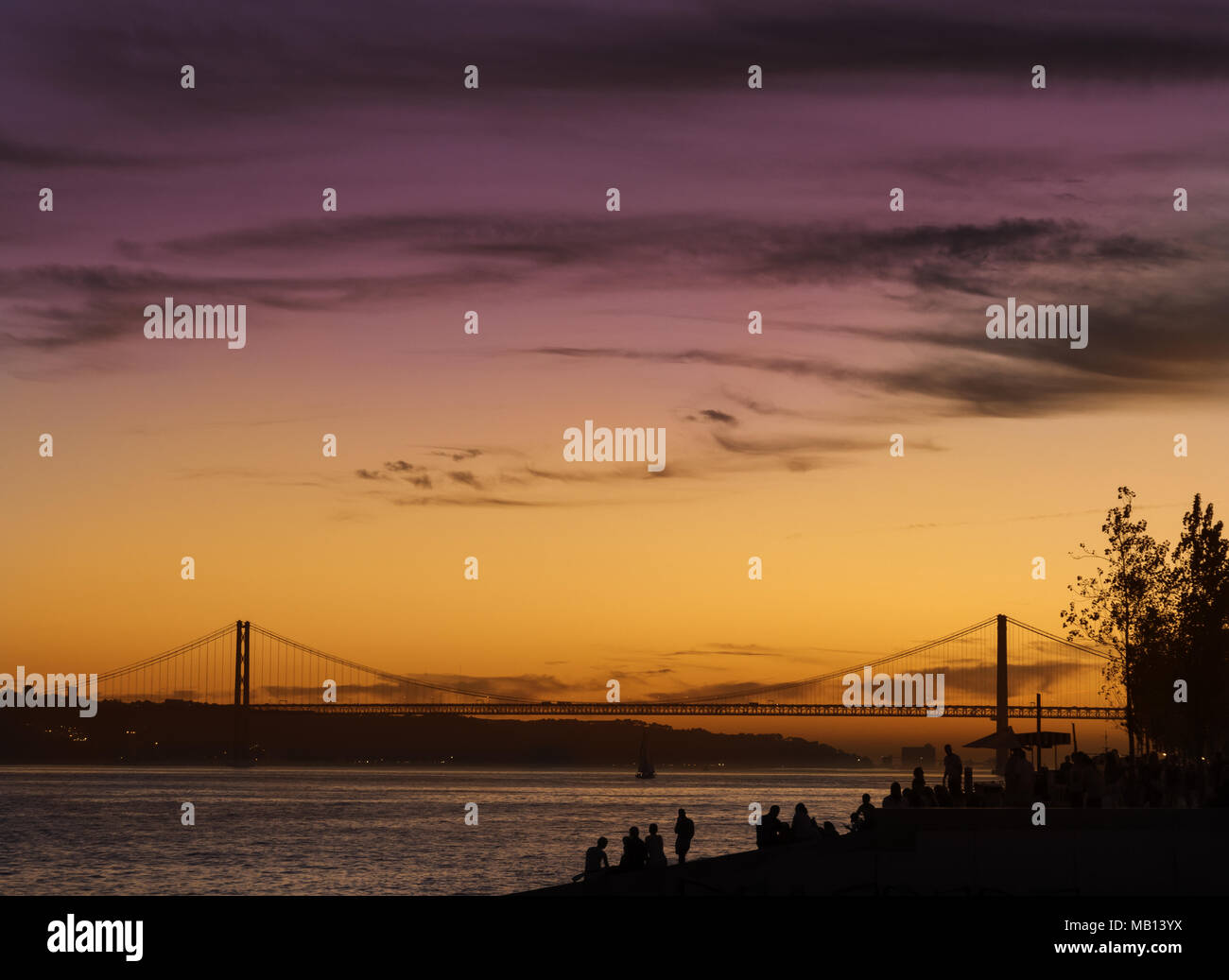 Schönen Sonnenuntergang lin Lissabon, Blick vom Praca do Comercio in Richtung Brücke "25 de Abril". Personen, die farbenprächtigen Sonnenuntergang. Stockfoto