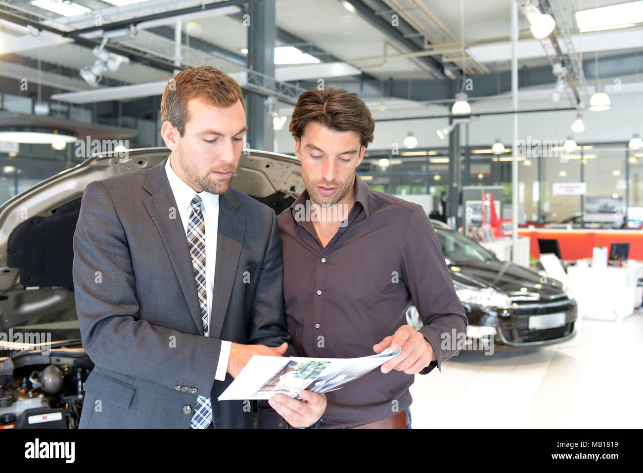 Auto Verkäufer und Kunden sprechen über die Technik eines Autos im Showroom des Autohauses Stockfoto