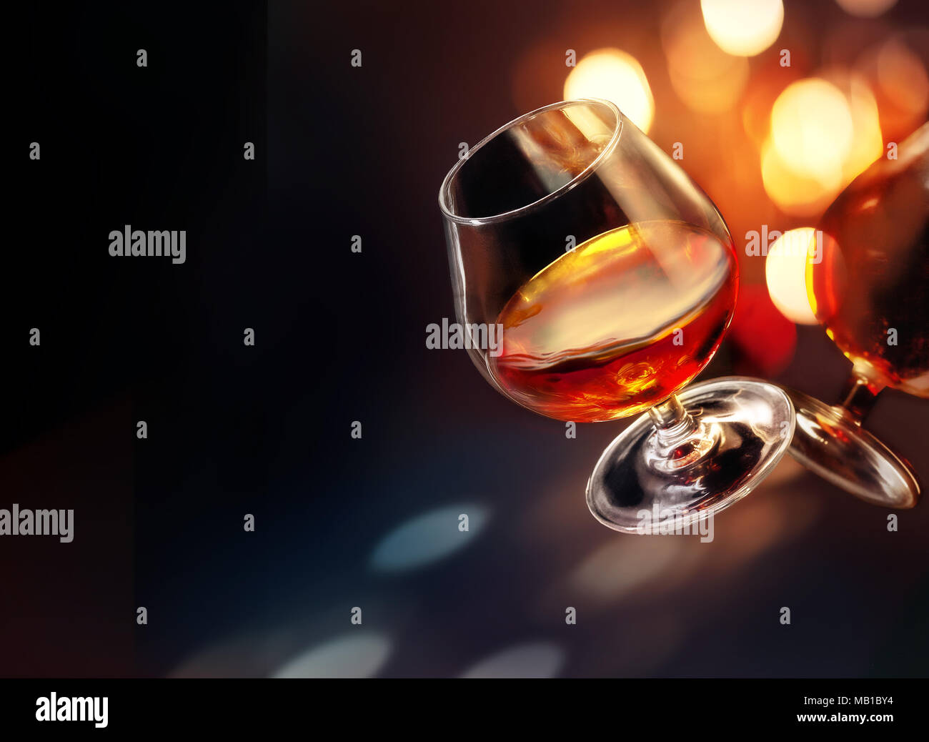 Gekippt wineglass von Cognac mit bunten helle Beleuchtung auf schwarzem Hintergrund Stockfoto