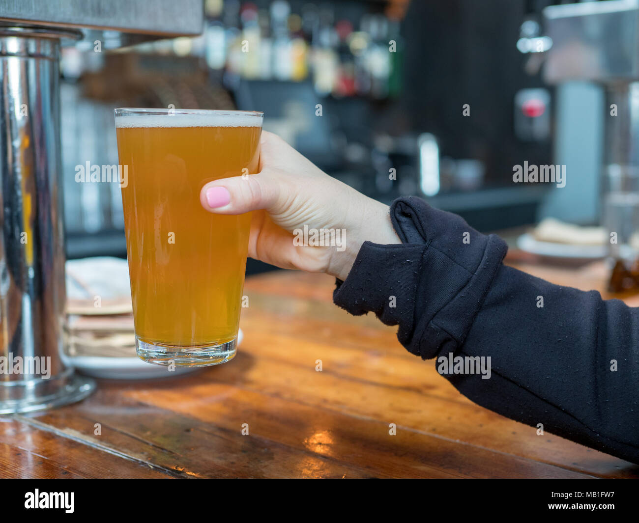 Frau Anheben pint Glas IPA Bier in einer Bar in einer Brauerei Stockfoto