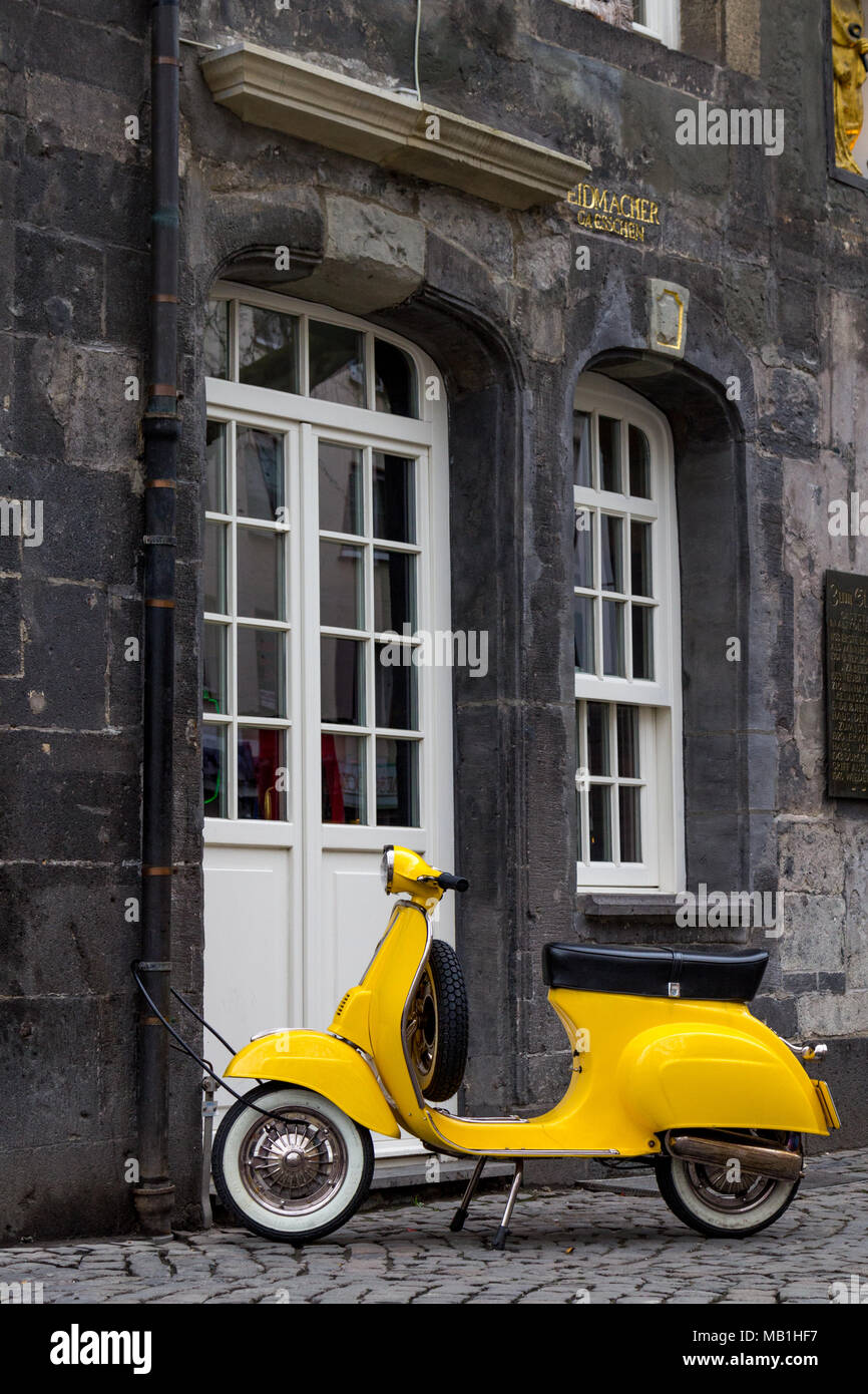 Eine gelbe alte Modell scooter zu einem regen Leitung eines historischen Haus im Zentrum der deutschen Stadt Essen gesperrt. Stockfoto