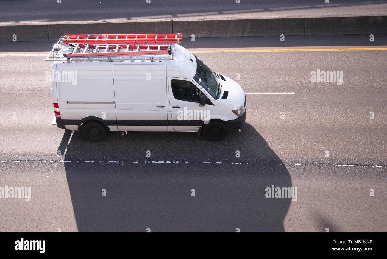 Kommerzielle cargo Mini Van mit langen Leiter auf dem Dach, die auf dem Weg zum Point of Service oder des Baugeschäfts Stockfoto