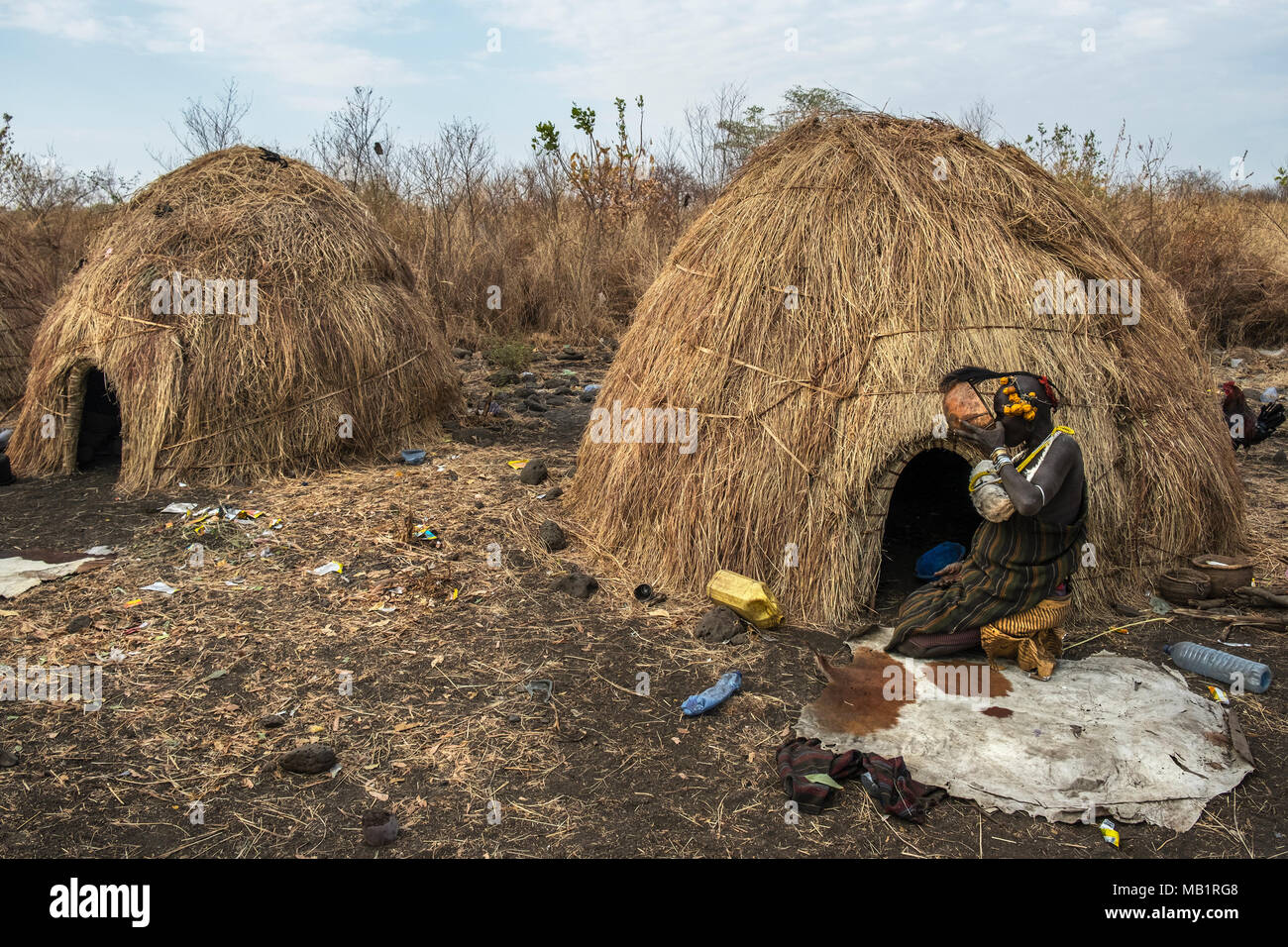 Omorate, Äthiopien - Januar 24, 2018: Frau der Mursi Stamm trinken in eine Schüssel neben ihrem Haus in einem traditionellen Dorf der Mursi in Äthiopien. Stockfoto