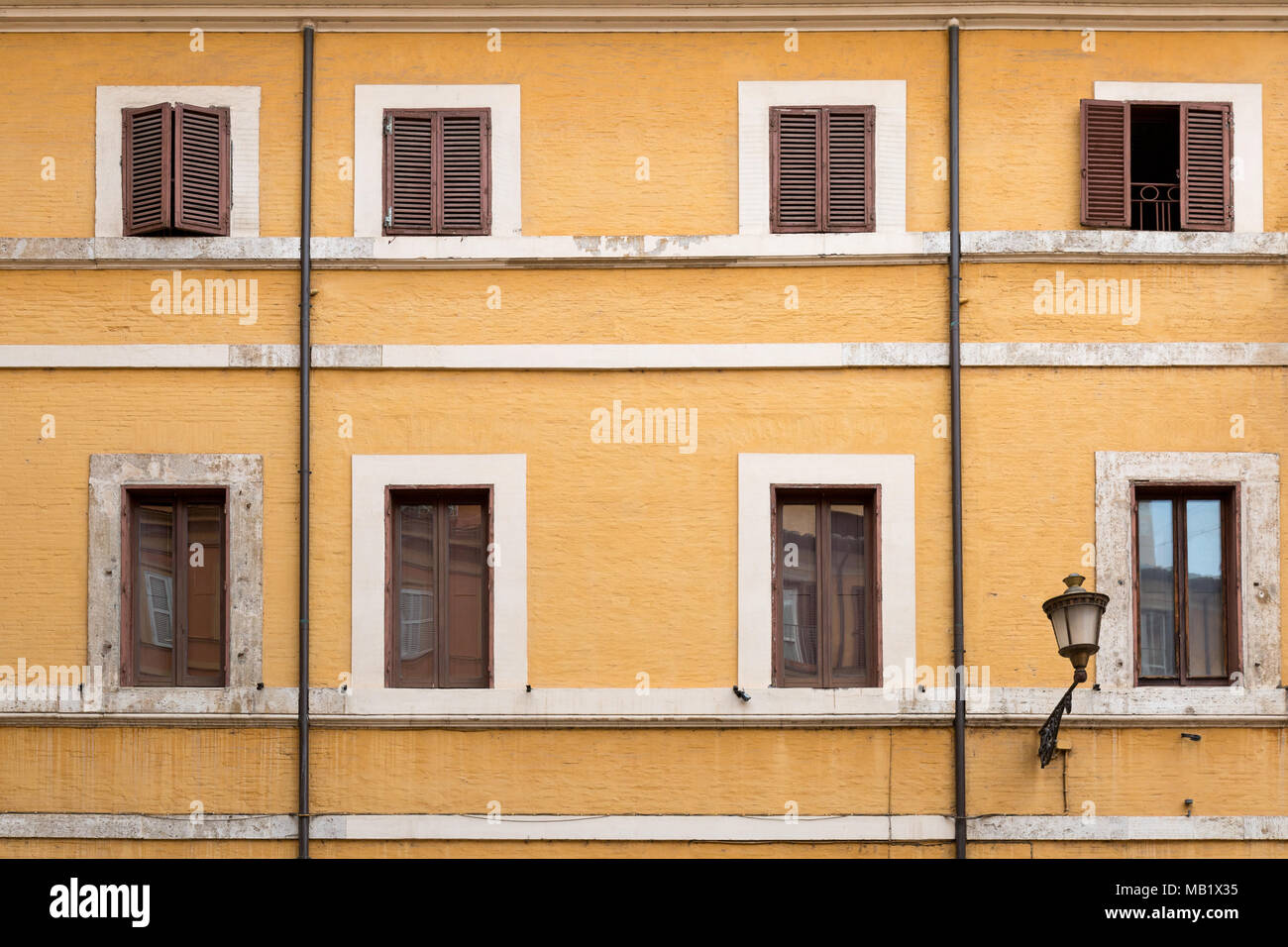 Ein Gebäude über den Straßen in Rom, Italien, mit Gelb lackiert Mauerwerk und Fensterläden aus Holz, einige der Lackierung neuer ist als der Rest! Diese hinzufügen Stockfoto