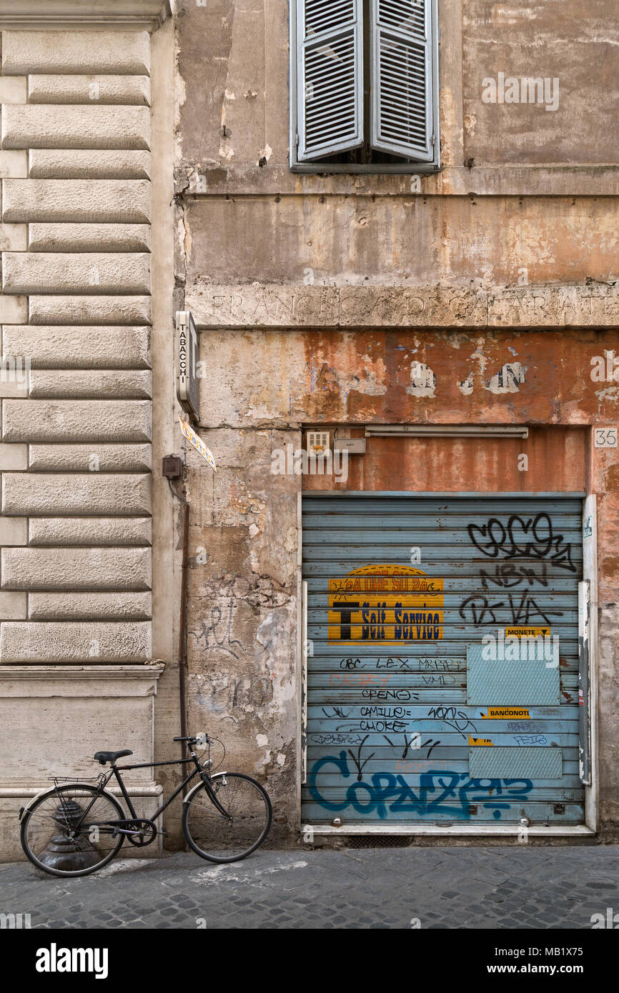 Ein altes Fahrrad an die Wand gelehnt eines Graffiti bedeckt Shutter, wo ein Self Service "Tabacchi" (TRAFIK) Einmal war, eine Szene aus der Rückseite stree Stockfoto